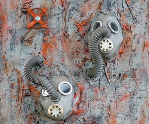 Only Two • Mixed Media, Tar, Plaster Wrap and Acrylic on Panel with World War I Gas Masks and Faucet Valve, Sonic (Singing) Interactive: Speakers mounted at hose end with sound exiting mask’s speaker, Electronics mounted on back, 24 X 18 inches (61 x 46 cm)